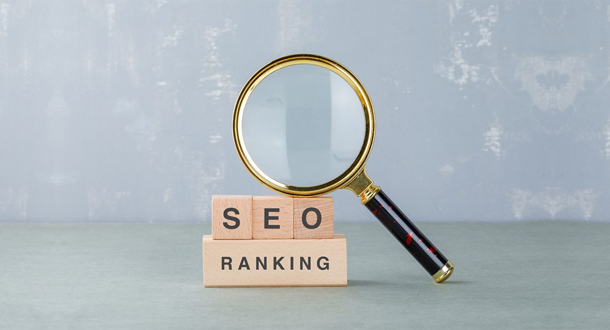 Magnifying glass focusing on wooden blocks displaying "SEO" and "RANKING," symbolizing digital marketing strategies for improving online visibility and search engine optimization.