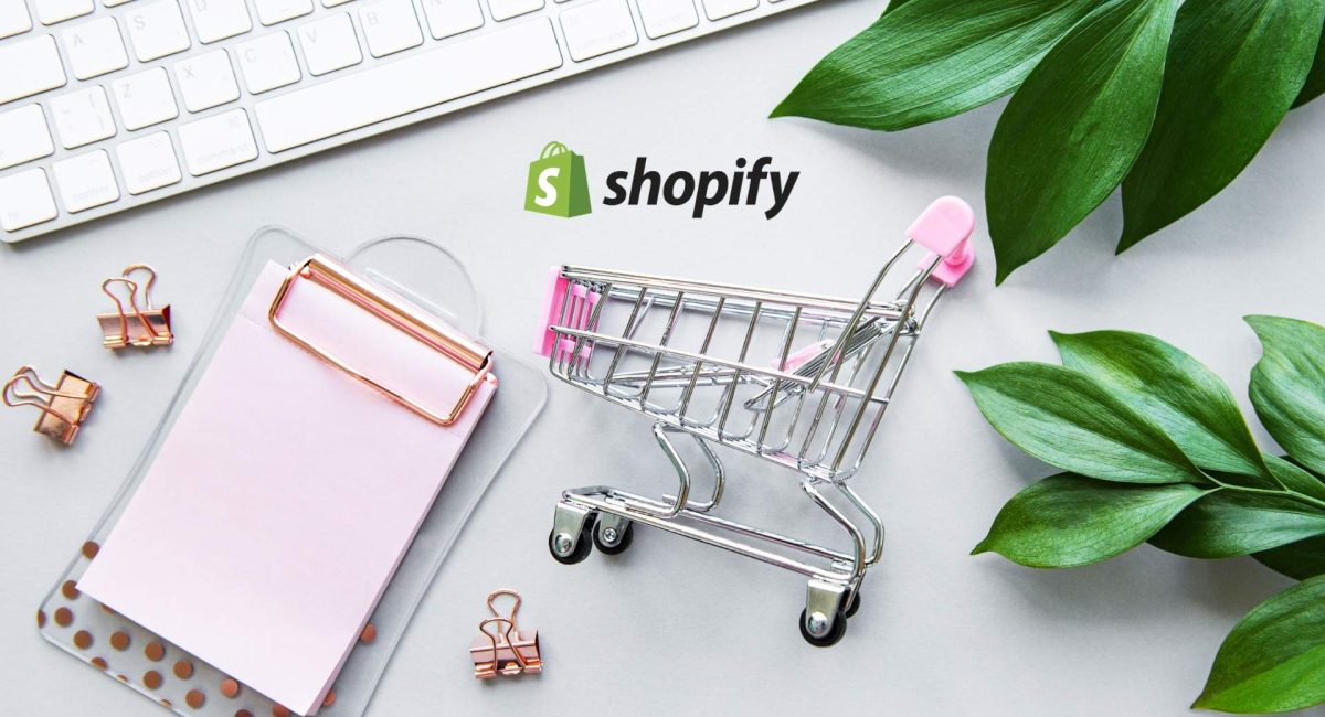 Miniature shopping cart beside a clipboard and keyboard, featuring the Shopify logo, representing e-commerce solutions and online store management in Australia.